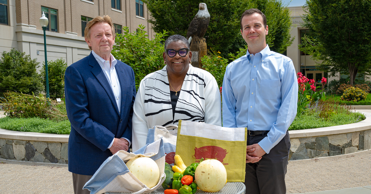 Alumni Neil Kerwin, Bronté Burleigh-Jones, and Michael Scher pose with fresh produce, all Airlie CSA offerings.