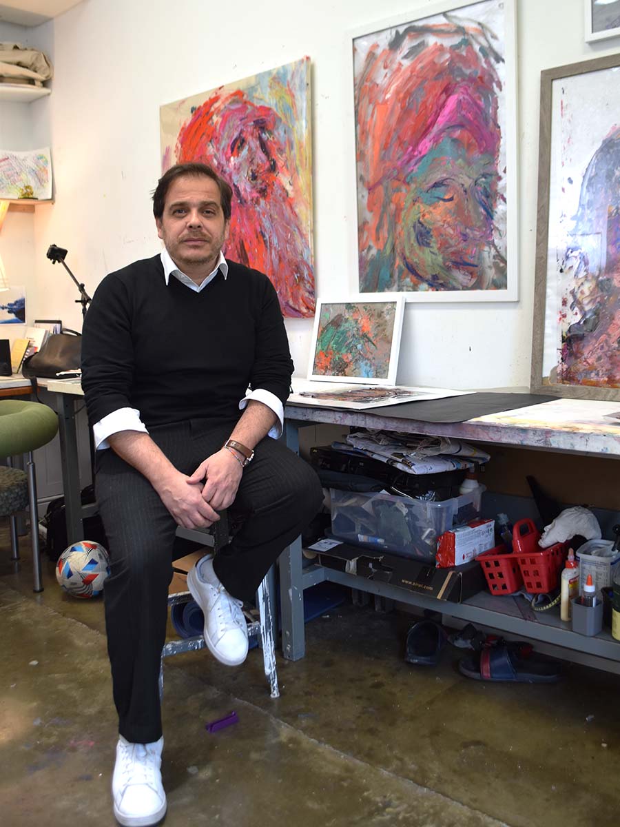 Andres Izquierdo seated in front of his paintings in his studio