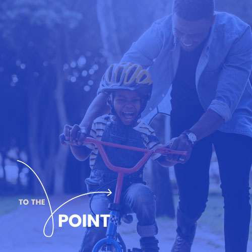 'To the Point.' A father helps his son ride a bicycle.