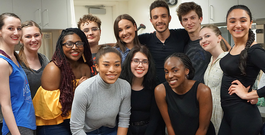 Dancers stand together and smile backstage during a performance