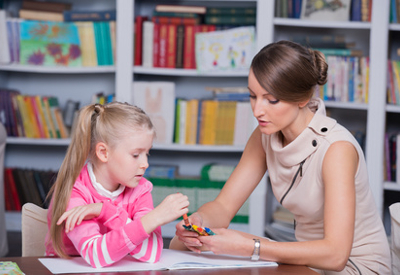 A child selects a crayon from the teacher's outstretched hand