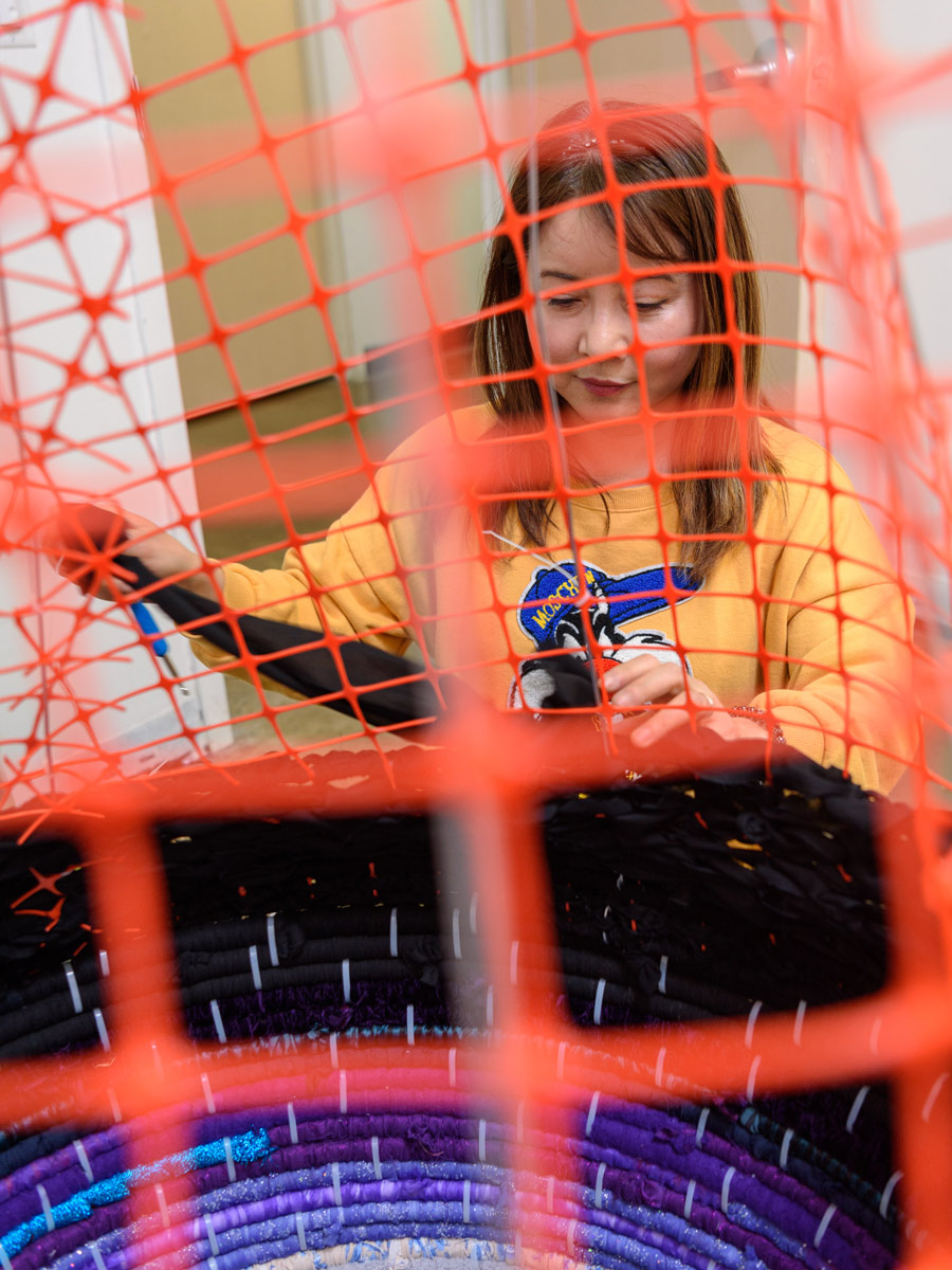 Hyunsuk Erickson works on a sculpture made from orange fencing mesh