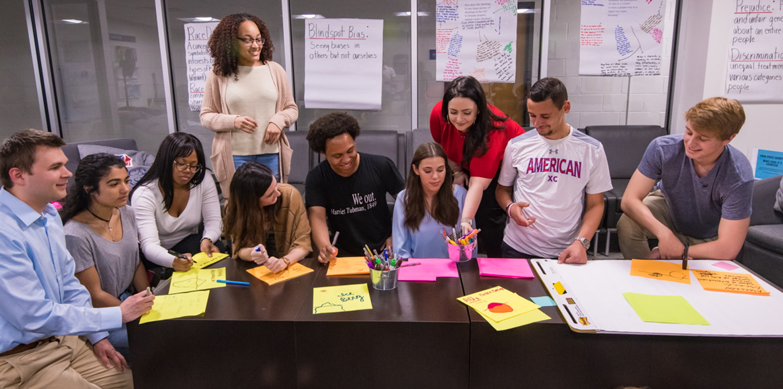 A group of 10 students work on an academic exercise at a table.