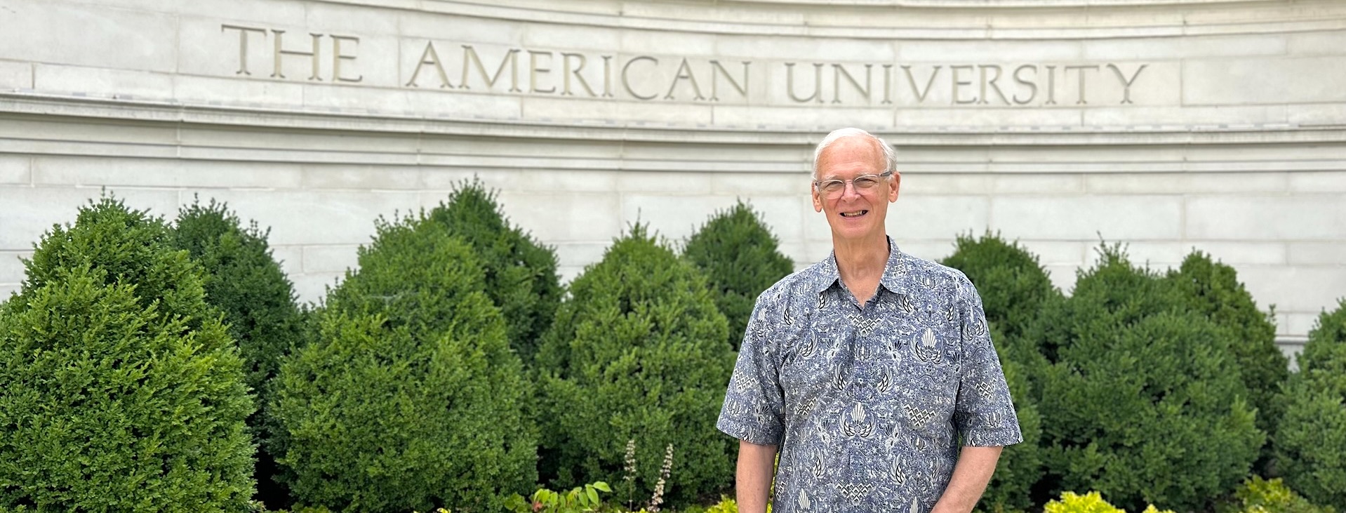 Gary Wright standing in front of the American University gate on campus.