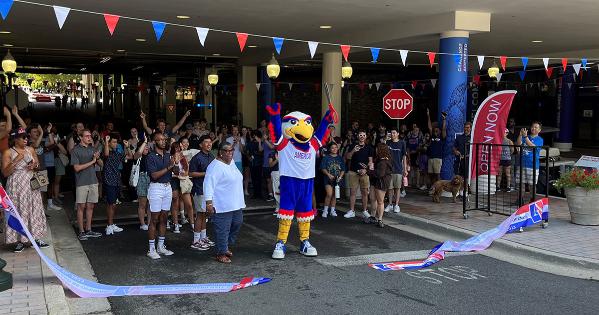 Clawed cutting a ribbon and celebrating in front of a crowd in the tunnel on campus.