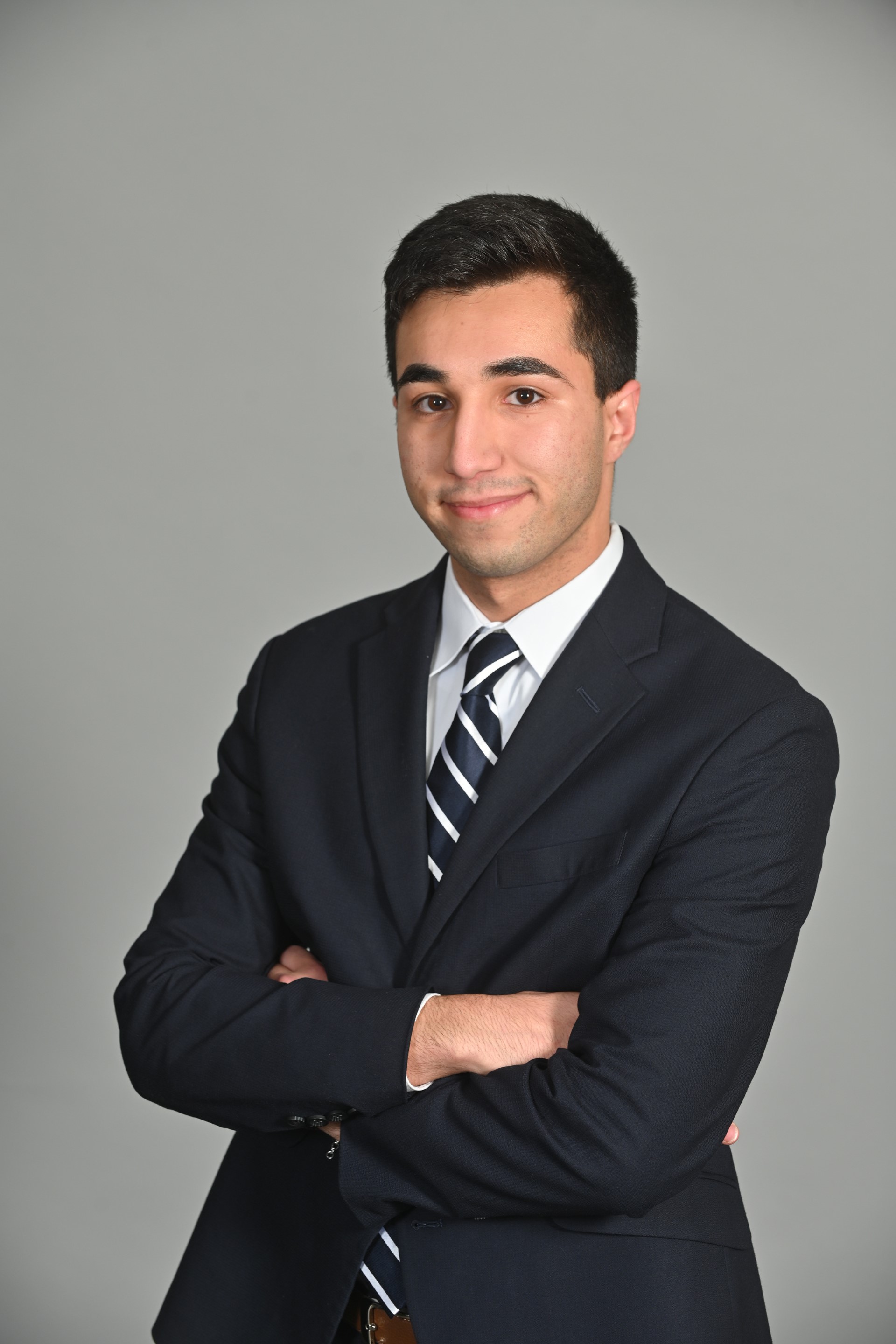 Ashkon posing in a black suit in front of a grey background