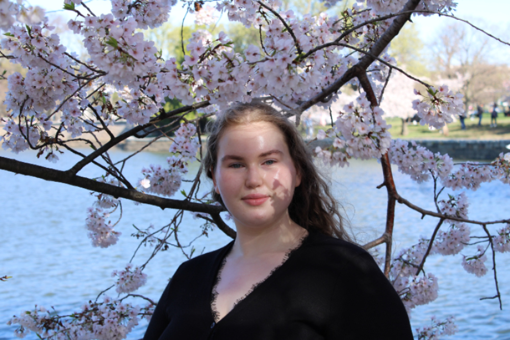 Vivian wearing black standing in front of cherry blossoms in full bloom