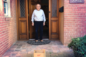 an elderly man stands in the doorway of his house