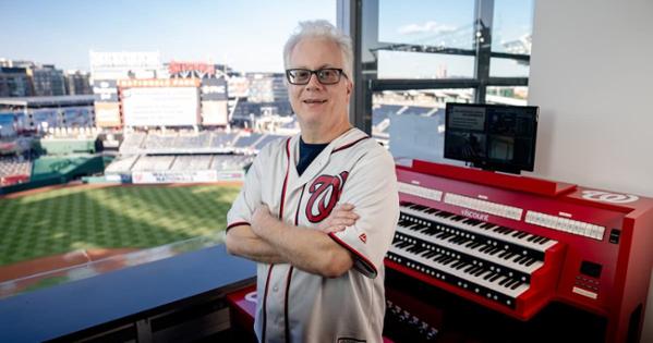 Matthew Van Hoose poses in front of a cherry red Viscount Sonus 60 in the press box. Courtesy of the Washington Nationals Baseball Club.