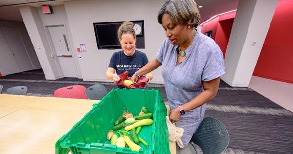 Dawnita Altieri hands produce to her colleague, Allison Kennedy. Photo by Jeff Watts.