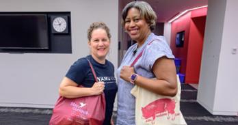 From left, WAMU colleagues Allison Kennedy and Dawnita Altieri show off their haul after sharing the weekly box of the Airlie Berkshire Farm community-supported agriculture program. Photo by Jeff Watts.