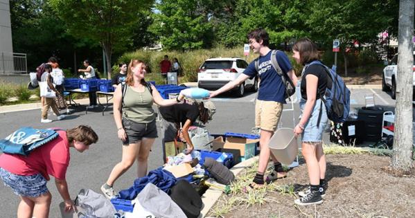 AU students smile as they pass an item to one another at the East Campus parking lot. Photo by Jeff Watts.