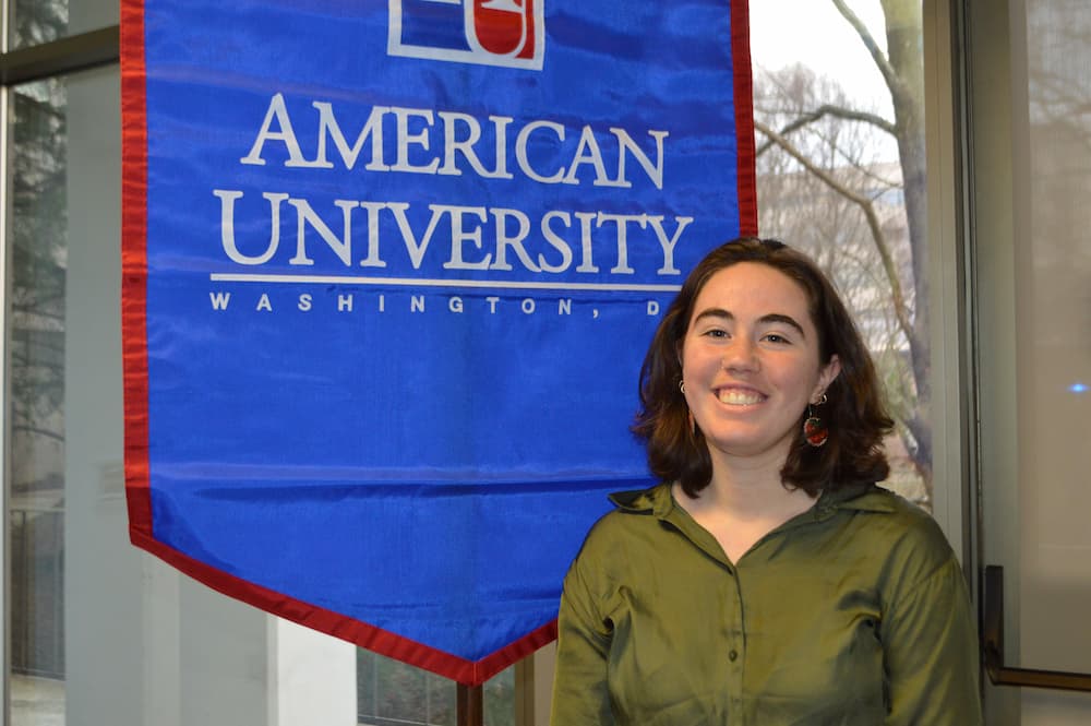 Katherine Raiano standing in front of AU banner