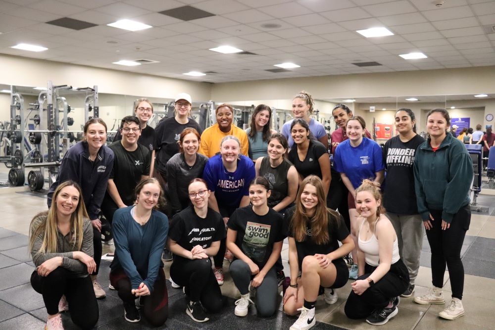 group of women posing in the fitness center weight room