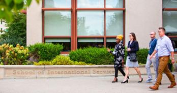 several students walk outside of the SIS building with "School of International Service" etched in stone