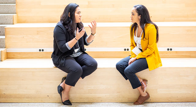 two girls sit on the spanish steps in SIS building talking