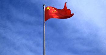 the chinese flag on a flagpole looking up to the sky