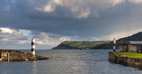 the ocean with a green hill in the distance and an entrance to a port