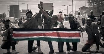 Youth protestors holding a Kenyan flag and raising their fists participate in the Kenya Gen Z protests in June 2024.