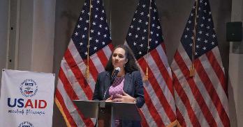 SIS alumna Lauren Reese speaks at a podium at a USAID event