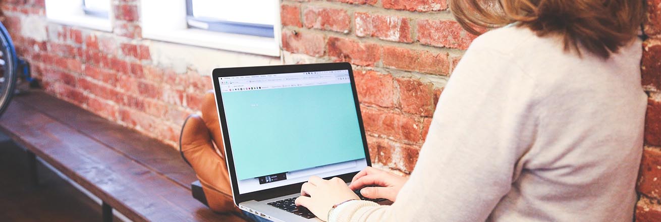 girl sits on a bench typing on a laptop