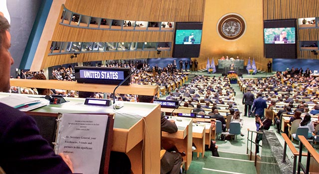 Then US Secretary of State John Kerry looks over meeting notes and across the packed room at the United Nations General Assembly Hall