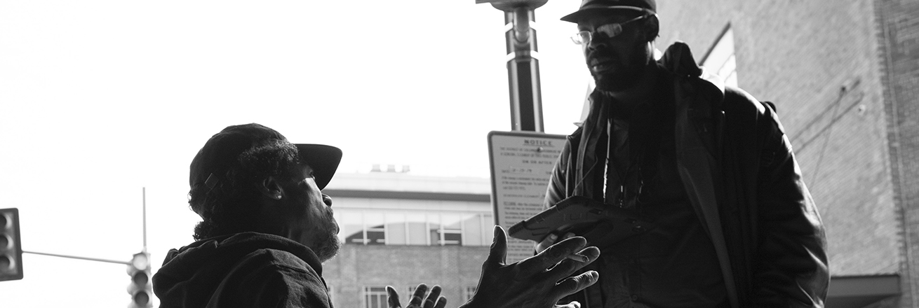 A man in a wheelchair talking with a man who is standing