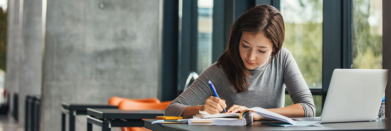 Woman writing notes at computer.