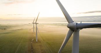 Three wind turbines on a grassy field.