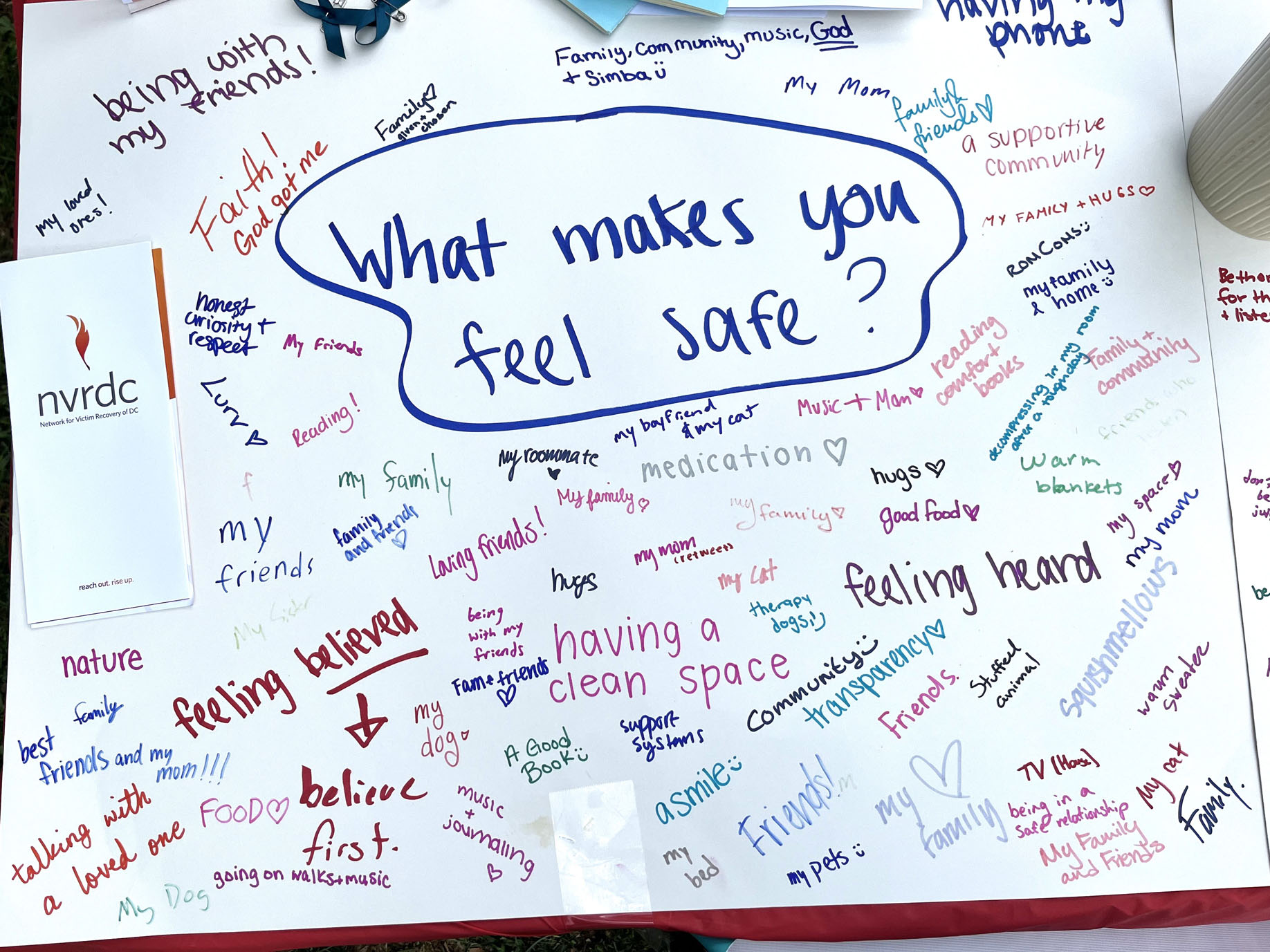 A photo of a piece of paper with "What make you feel safe?" written in the center. Many answers surround it, like "feeling heard" or "faith" or "friends."
