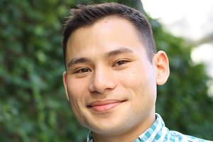 Man smiling in front of tree brush.