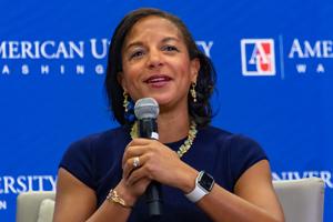 Woman smiling at event with microphone.